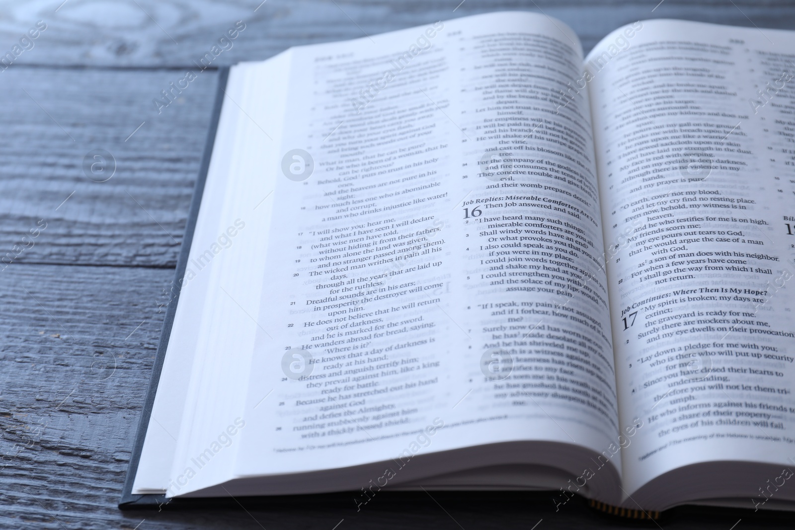 Photo of Open Holy Bible in English language on wooden table, closeup