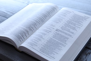 Photo of Open Holy Bible in English language on wooden table, closeup