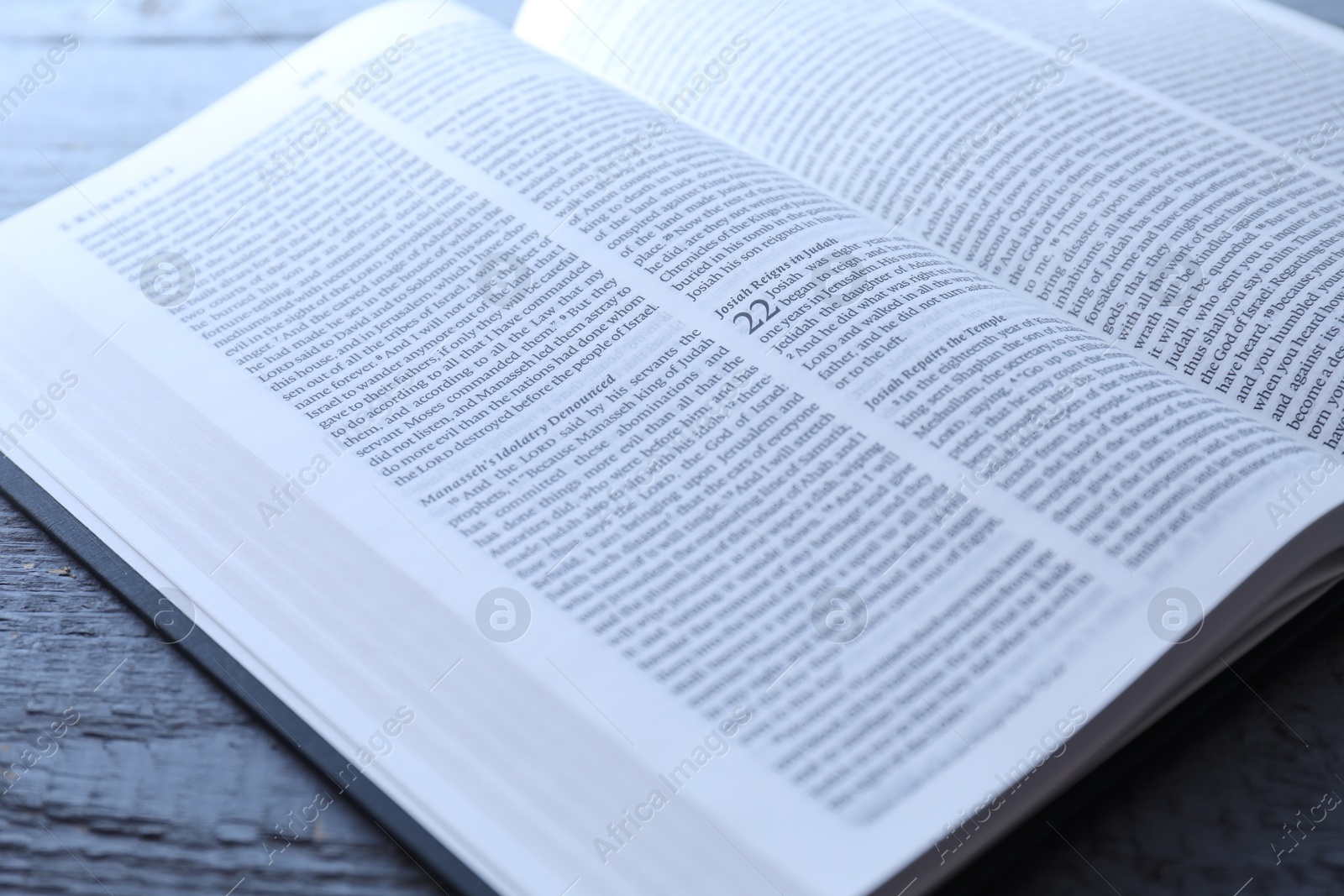 Photo of Open Holy Bible in English language on wooden table, closeup