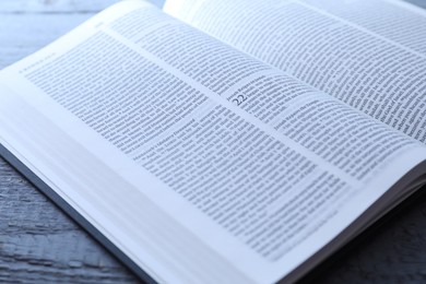 Photo of Open Holy Bible in English language on wooden table, closeup