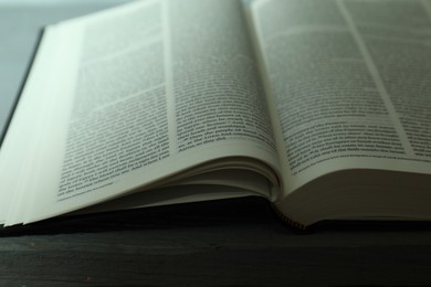 Photo of Open Holy Bible in English language on wooden table, closeup