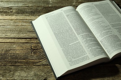 Photo of Open Holy Bible in English language on wooden table, closeup