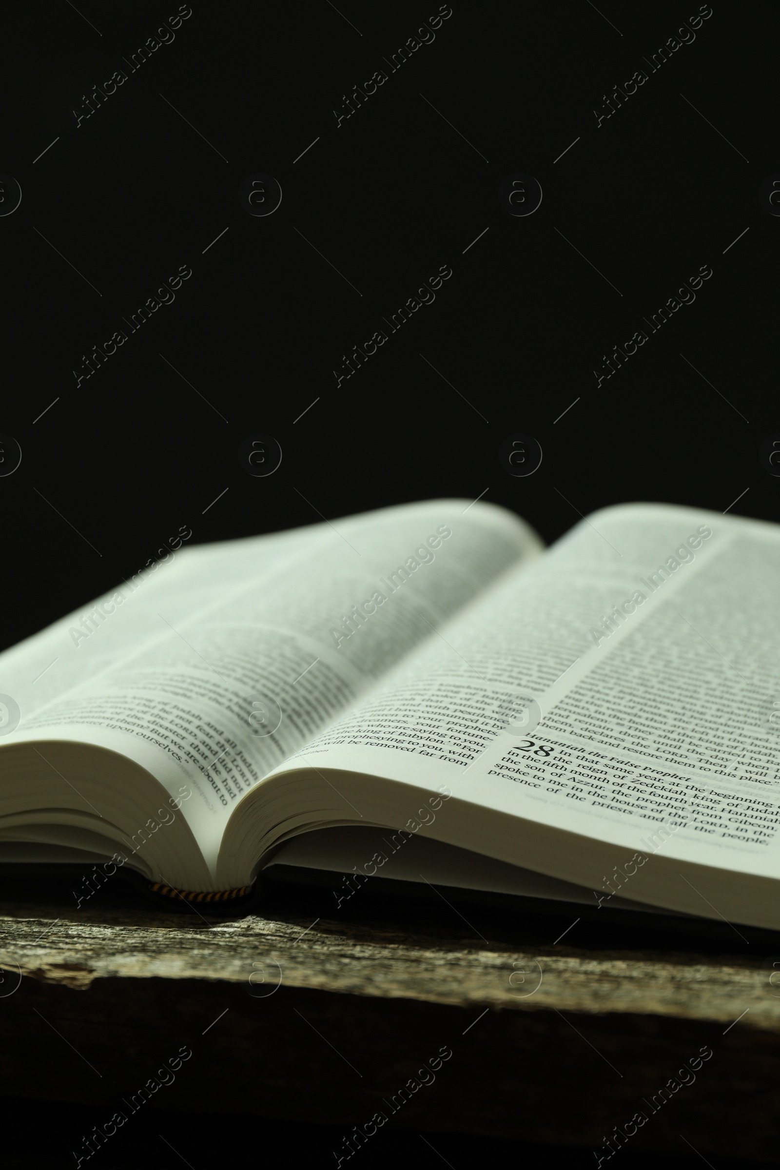 Photo of Open Holy Bible in English language on wooden table, closeup