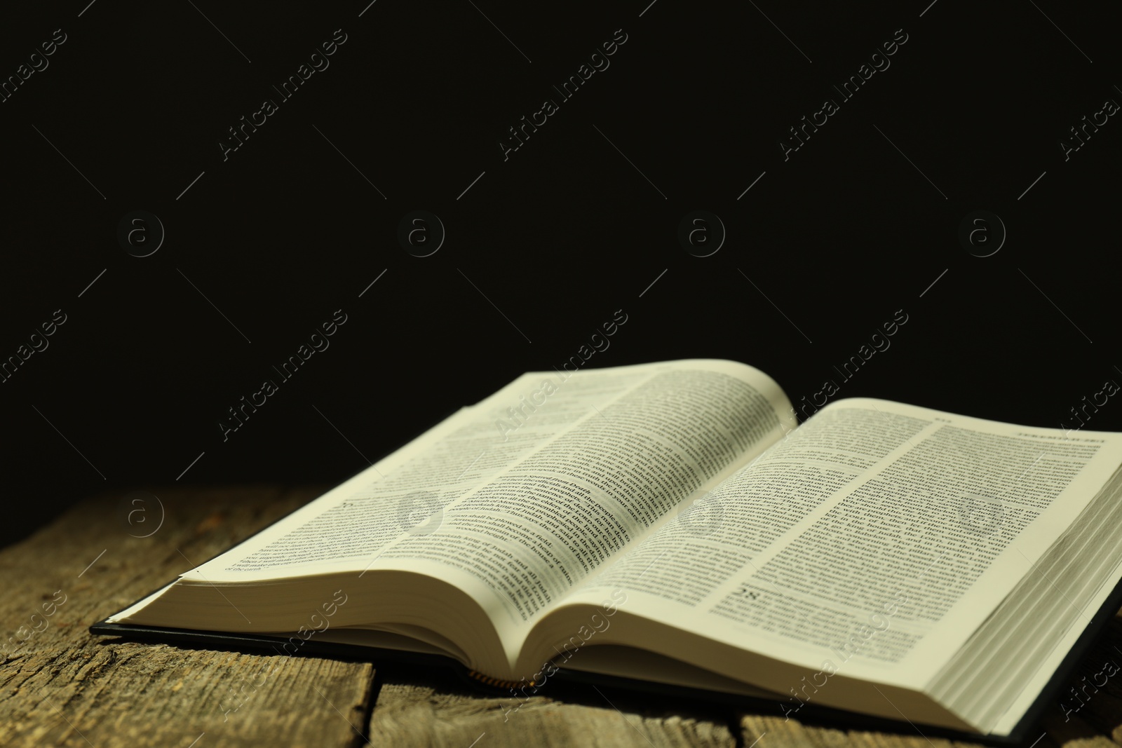 Photo of Open Holy Bible in English language on wooden table. Space for text