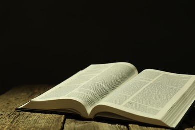 Photo of Open Holy Bible in English language on wooden table. Space for text