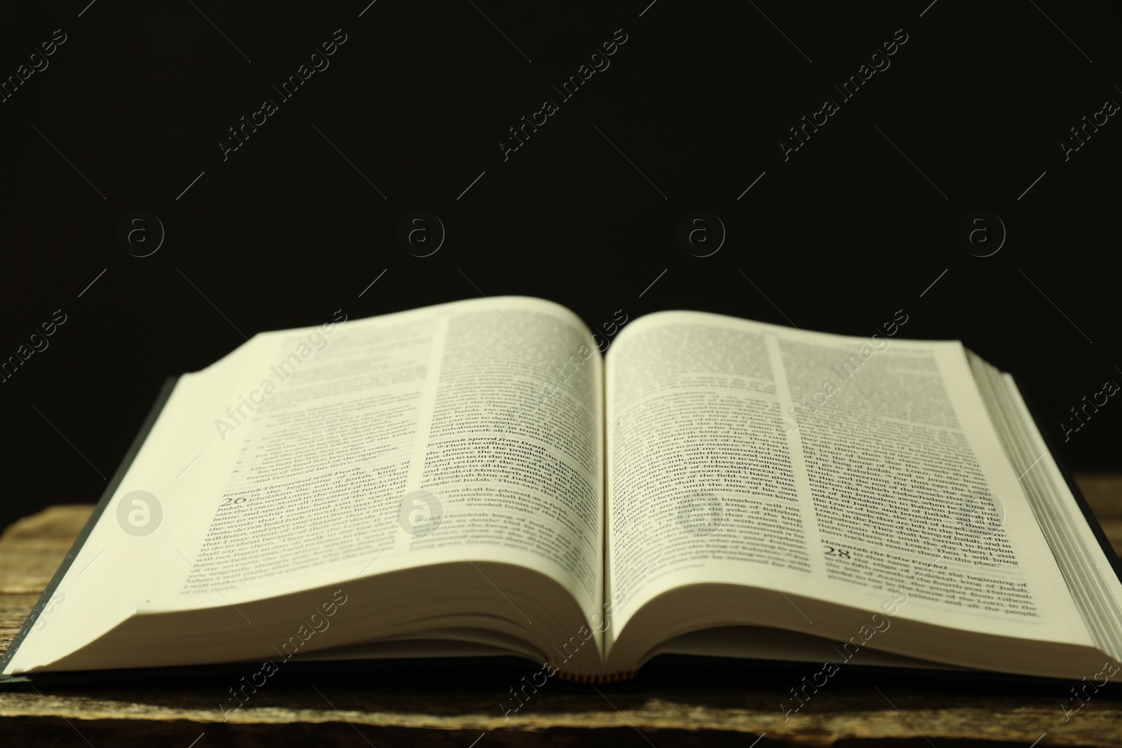 Photo of Open Holy Bible in English language on wooden table, closeup. Space for text