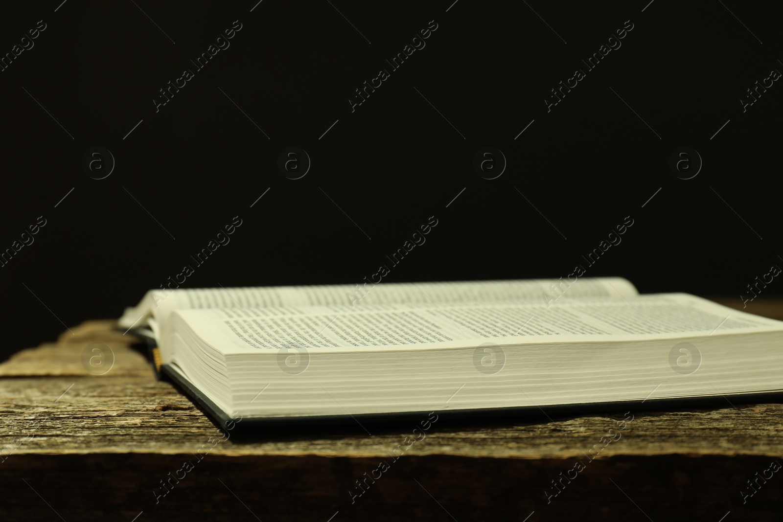 Photo of Open Holy Bible in English language on wooden table, closeup. Space for text