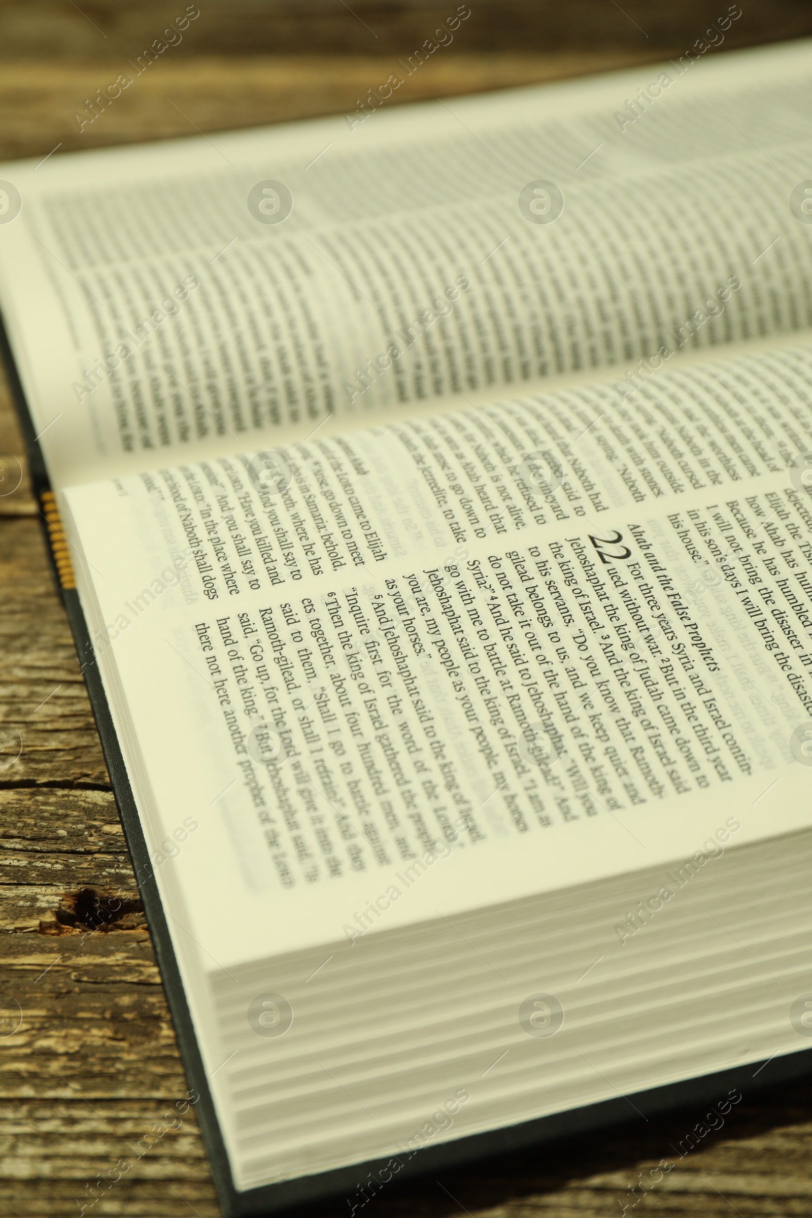 Photo of Open Holy Bible in English language on wooden table, closeup