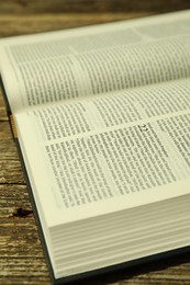 Photo of Open Holy Bible in English language on wooden table, closeup