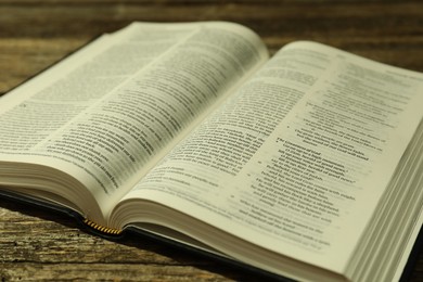 Photo of Open Holy Bible in English language on wooden table, closeup