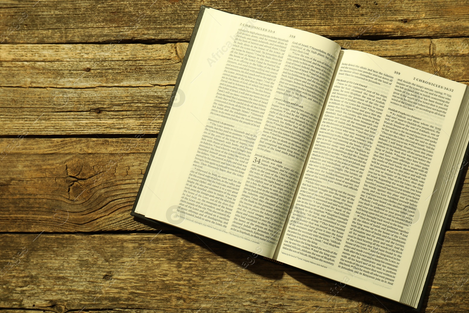 Photo of Open Holy Bible in English language on wooden table, top view