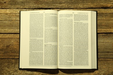 Open Holy Bible in English language on wooden table, top view