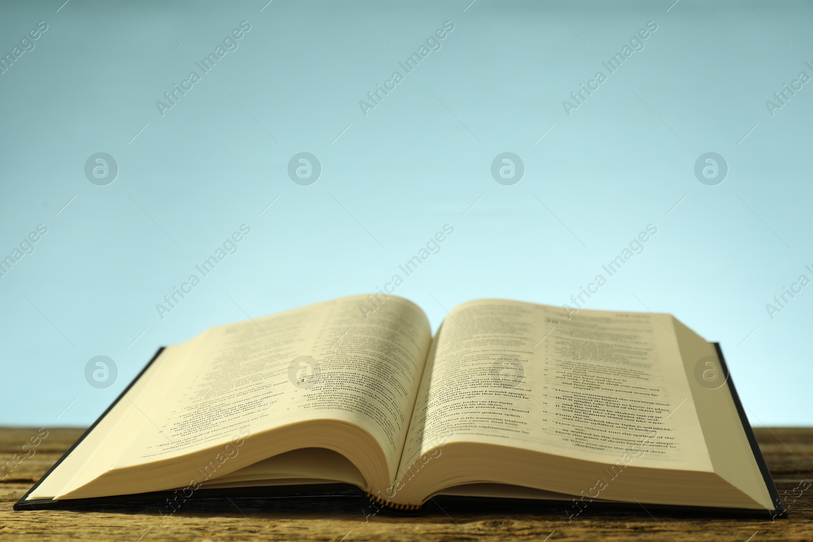 Photo of Open Holy Bible in English language on wooden table. Space for text