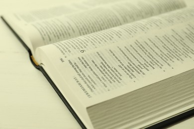 Open Holy Bible in English language on white table, closeup