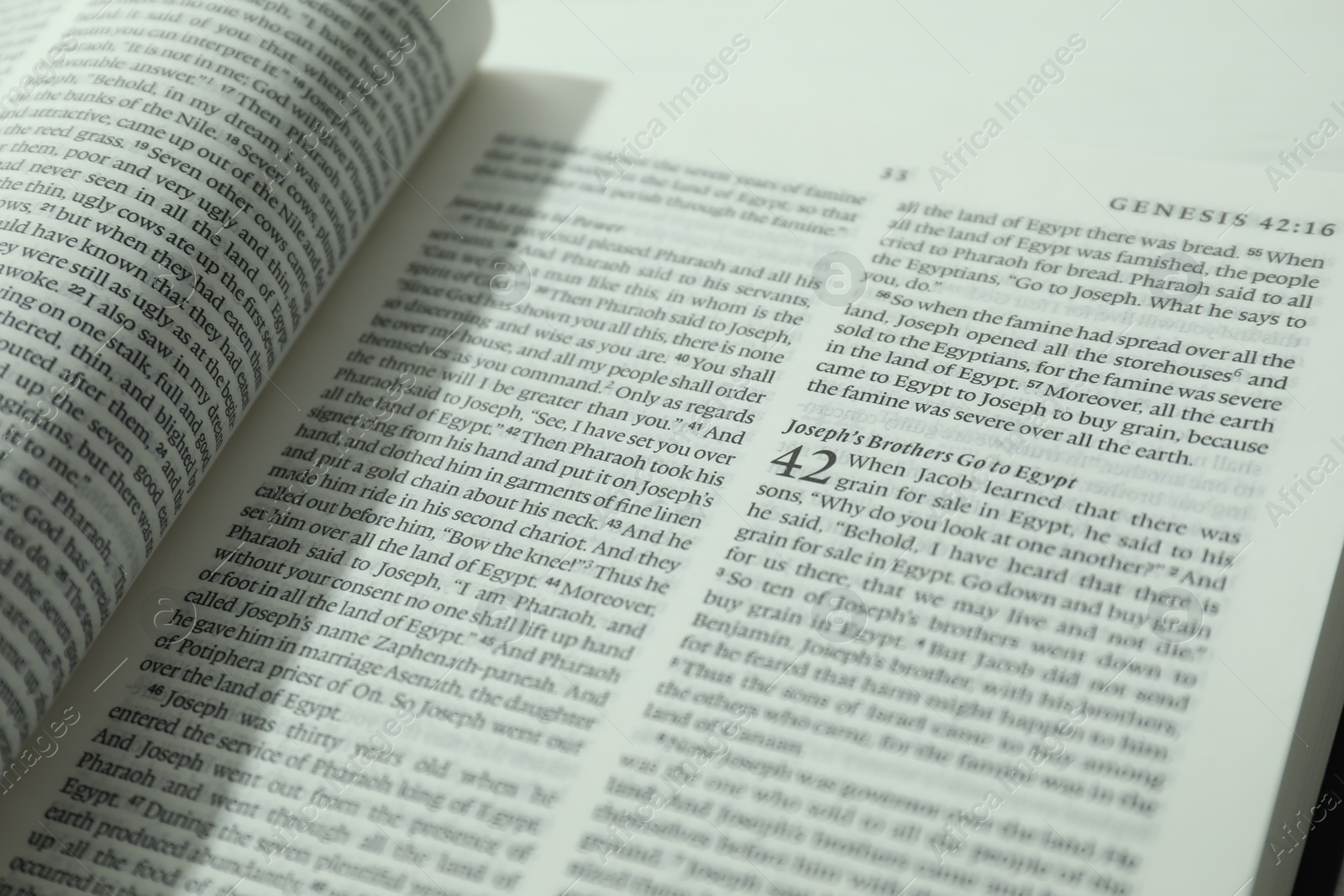 Photo of Open Holy Bible in English language on table, closeup