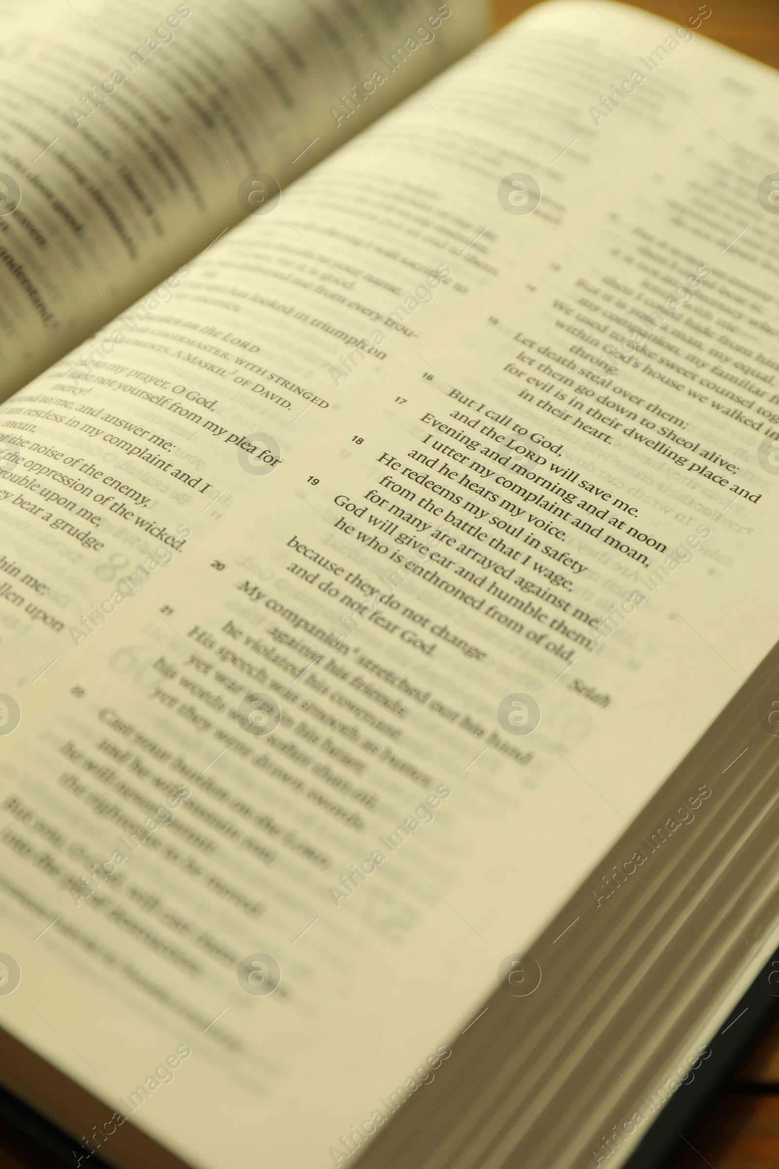 Photo of Open Holy Bible in English language on wooden table, closeup