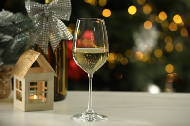 Photo of Glass of white wine and Christmas decor on table against blurred lights, space for text. Bokeh effect