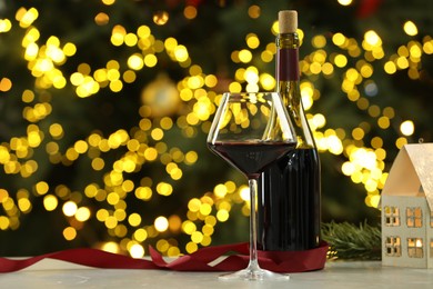 Photo of Glass of red wine and Christmas decor on table against blurred lights, space for text. Bokeh effect