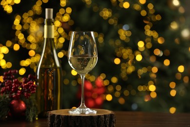 Photo of Glass and bottle of white wine with Christmas decor on wooden table against blurred lights, space for text. Bokeh effect