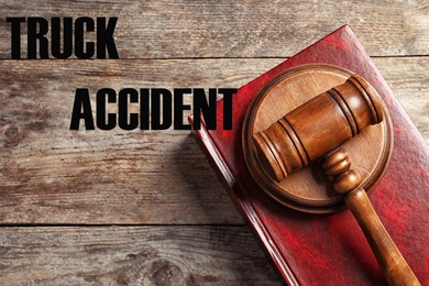 Image of Truck accident law. Judge's gavel and book on wooden table, top view