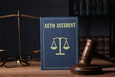 Image of Auto Accident law book, judge's gavel, scales and glasses on wooden table