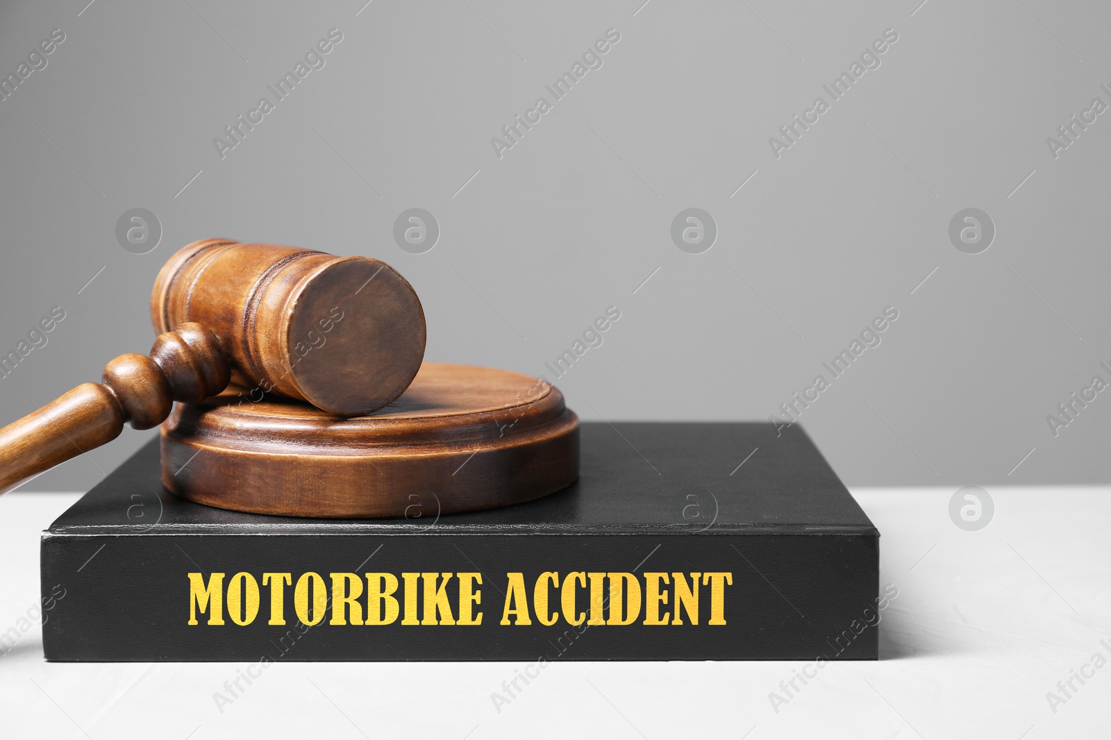 Image of Motorbike Accident law book and judge's gavel on light table against gray background, space for text