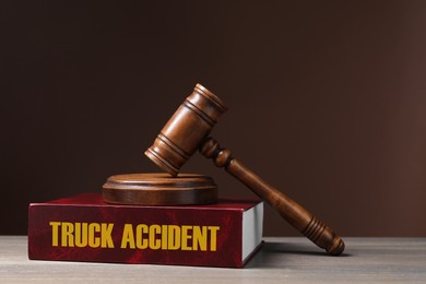 Truck Accident law book and judge's gavel on wooden table against brown background