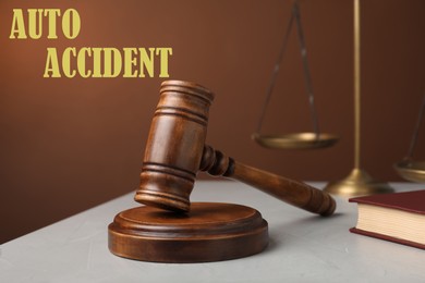 Image of Auto accident law. Judge's gavel, scales of justice and book on table against brown background