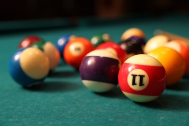 Photo of Many colorful billiard balls on green table, closeup