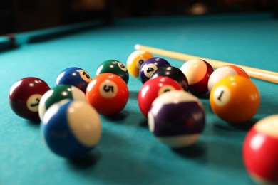 Photo of Many colorful billiard balls and cue on green table, closeup