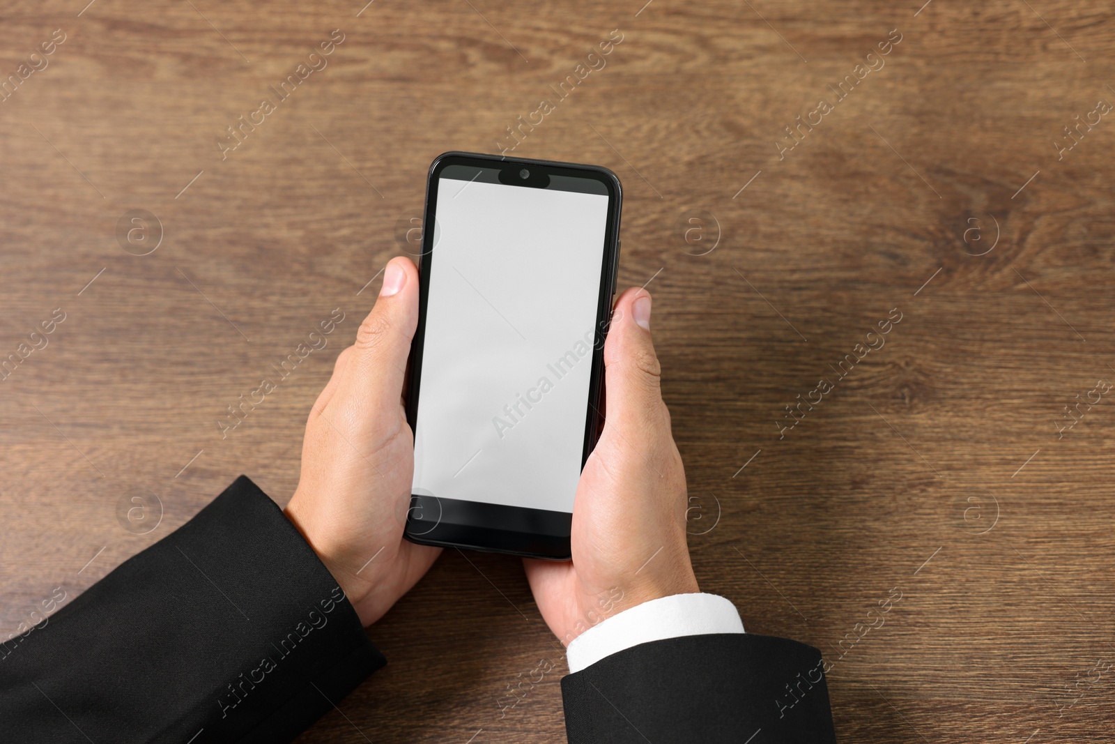 Photo of Man holding smartphone with fingerprint scanner at wooden table, closeup