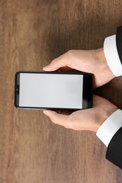 Photo of Man holding smartphone with fingerprint scanner at wooden table, closeup