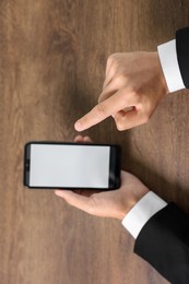 Photo of Man unlocking smartphone with fingerprint scanner at wooden table, closeup