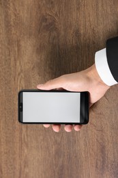 Photo of Man holding smartphone with fingerprint scanner at wooden table, closeup