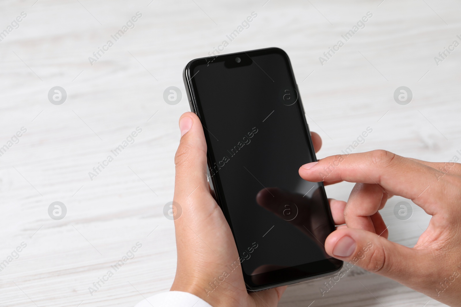 Photo of Man unlocking smartphone with fingerprint scanner at light wooden table, closeup