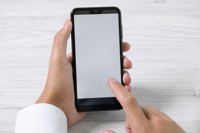 Photo of Man unlocking smartphone with fingerprint scanner at light wooden table, closeup