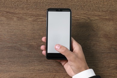 Photo of Man unlocking smartphone with fingerprint scanner at wooden table, top view