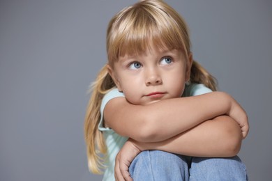 Photo of Orphanage concept. Sad little girl on grey background