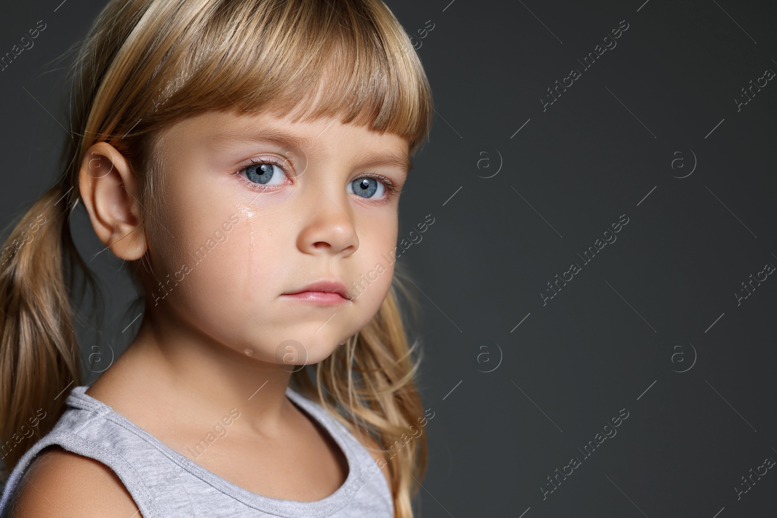 Photo of Orphanage concept. Sad little girl on grey background, space for text