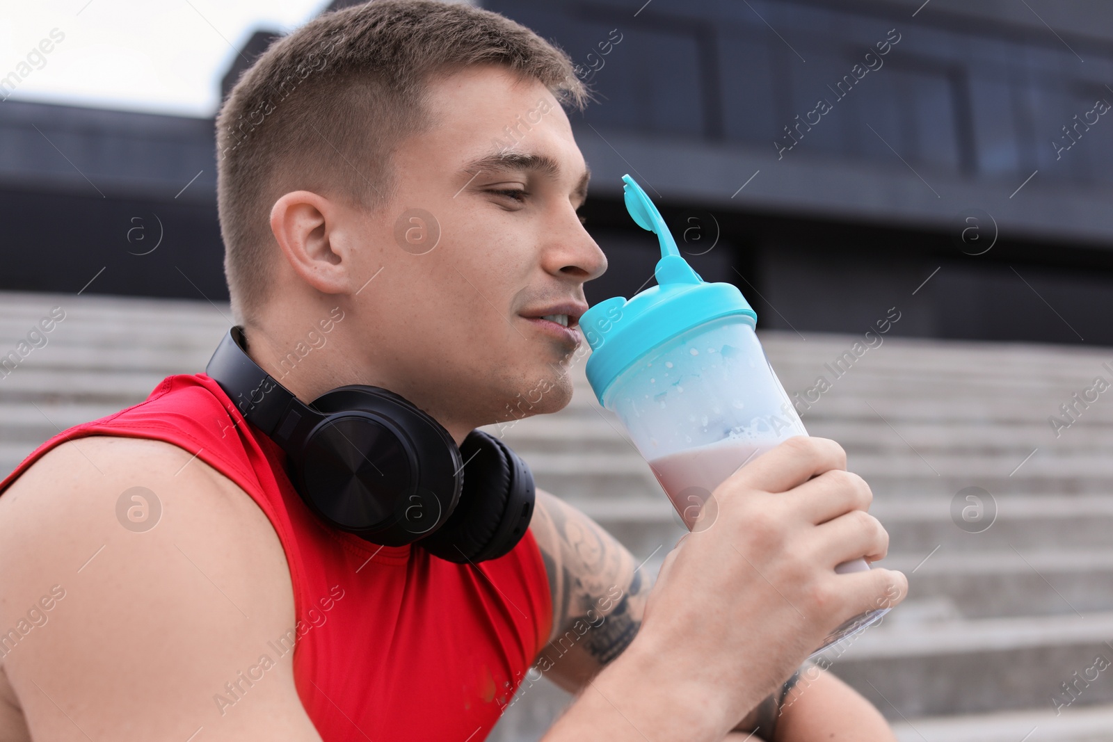 Photo of Handsome athletic man drinking protein shake outdoors