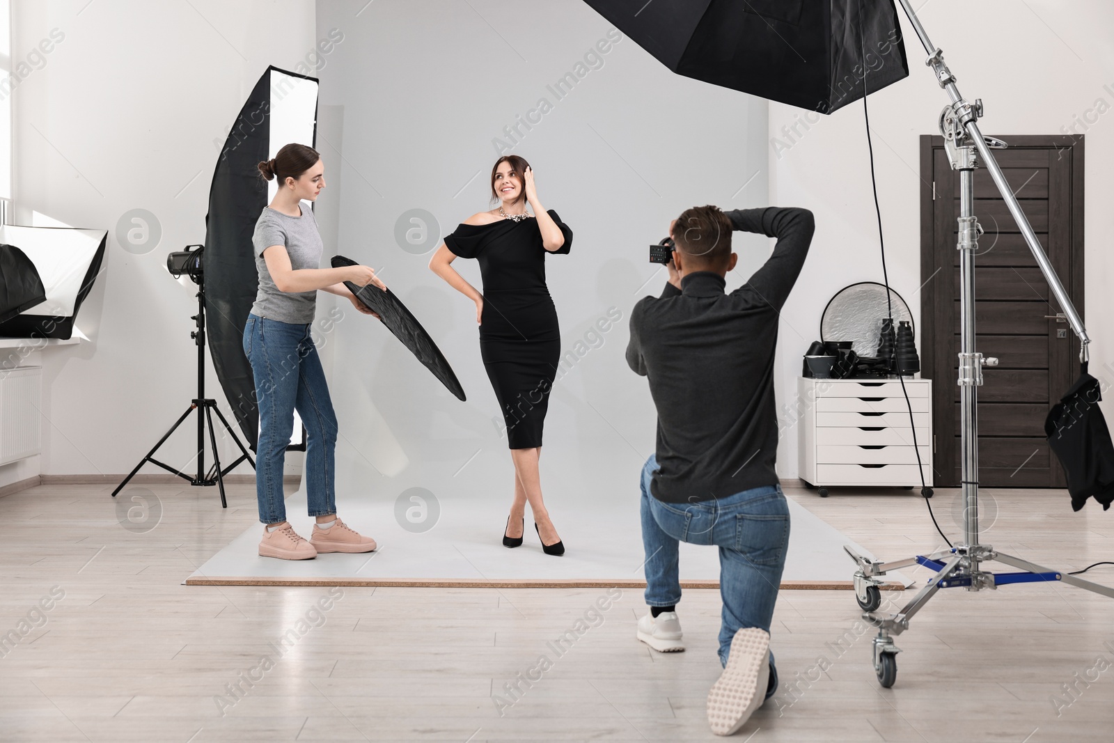 Photo of Photographer and assistant working with model in professional photo studio