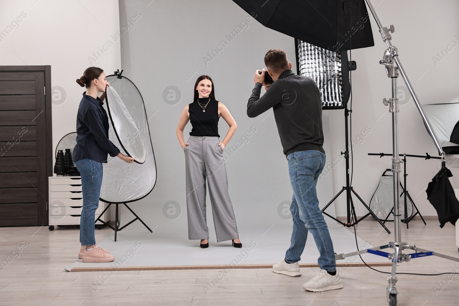 Photo of Photographer and assistant working with model in professional photo studio