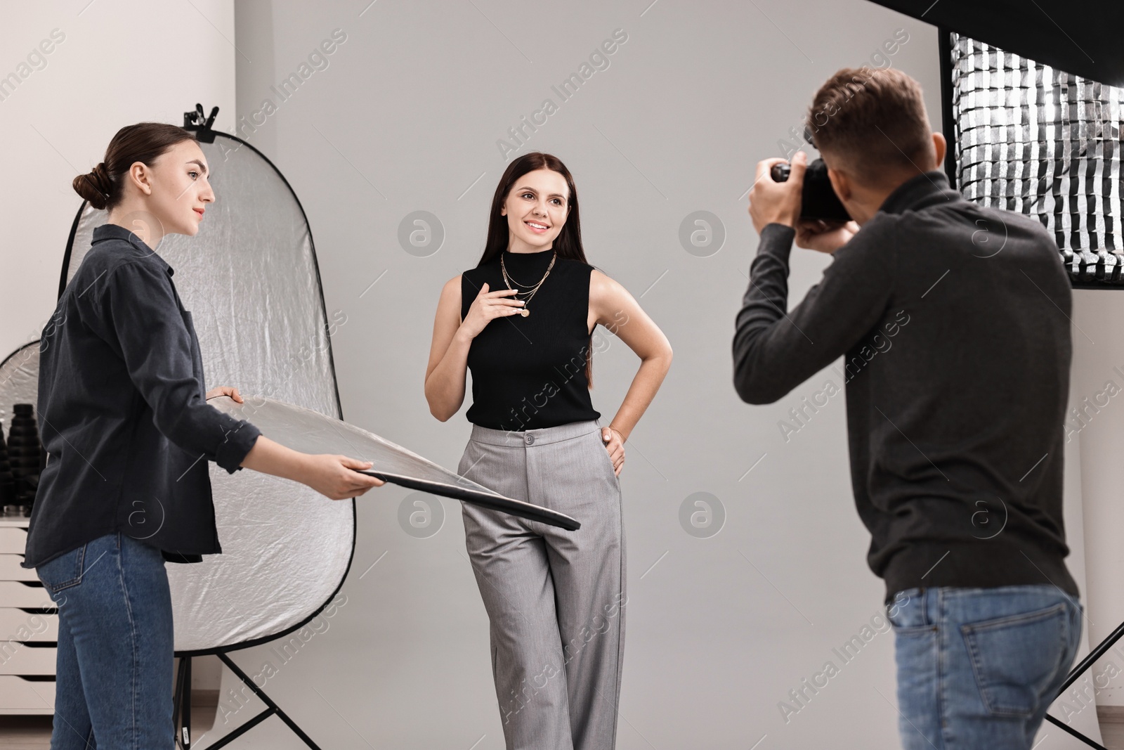 Photo of Photographer and assistant working with model in professional photo studio