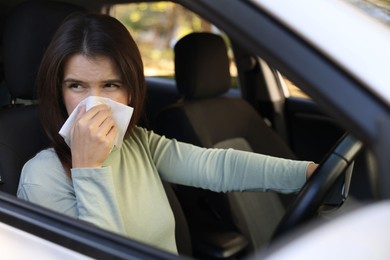 Young woman with runny nose in car