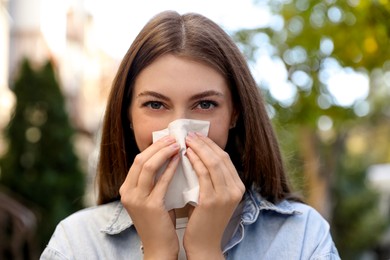 Young woman with runny nose in park