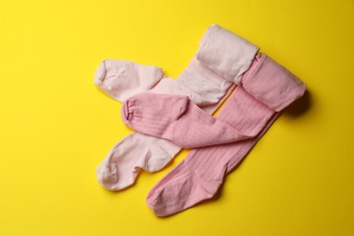 Photo of Pink child's tights on yellow background, top view