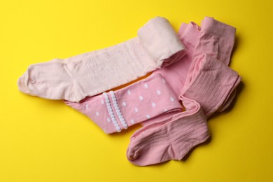 Photo of Pink child's tights on yellow background, flat lay