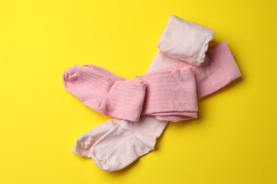 Photo of Pink child's tights on yellow background, top view