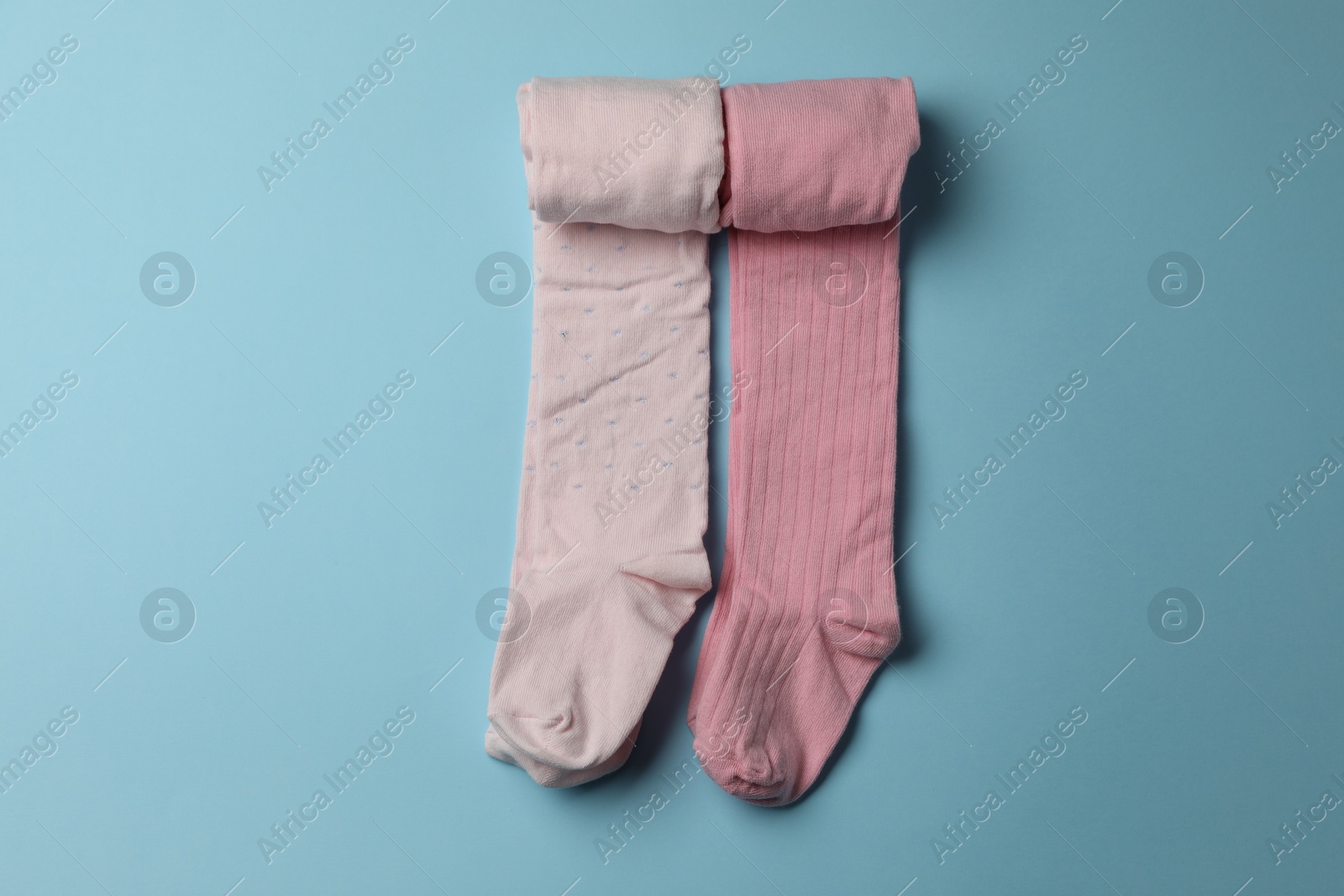 Photo of Pink child's tights on light blue background, top view