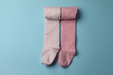 Photo of Pink child's tights on light blue background, top view